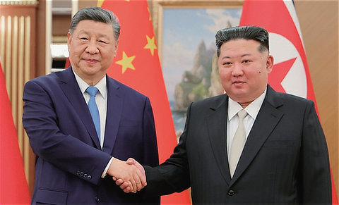 中朝首脳会談で連携強化を誇示した習近平国家主席と金正恩総書記が握手する姿を伝える写真